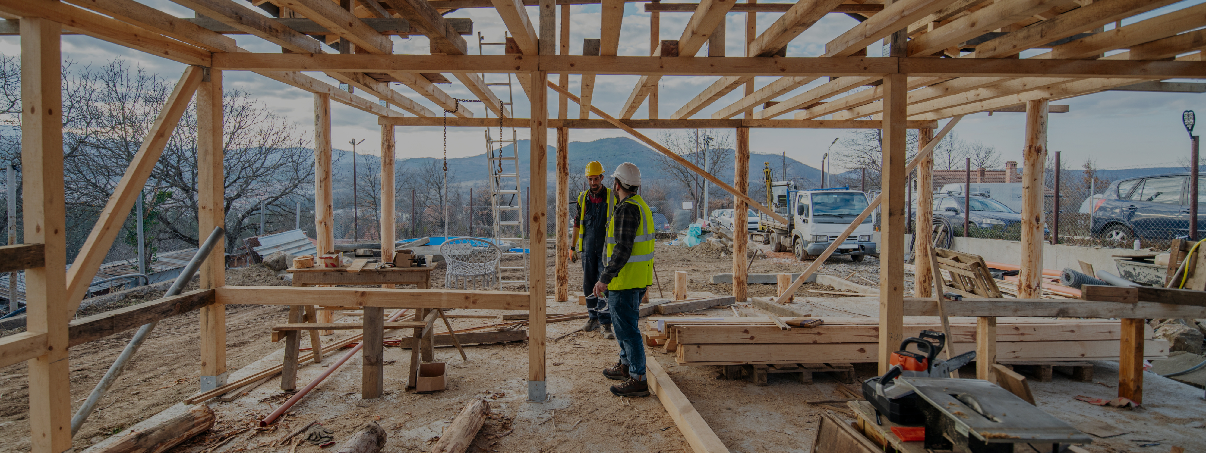 Two men in construction gear working inside an unfinished house.