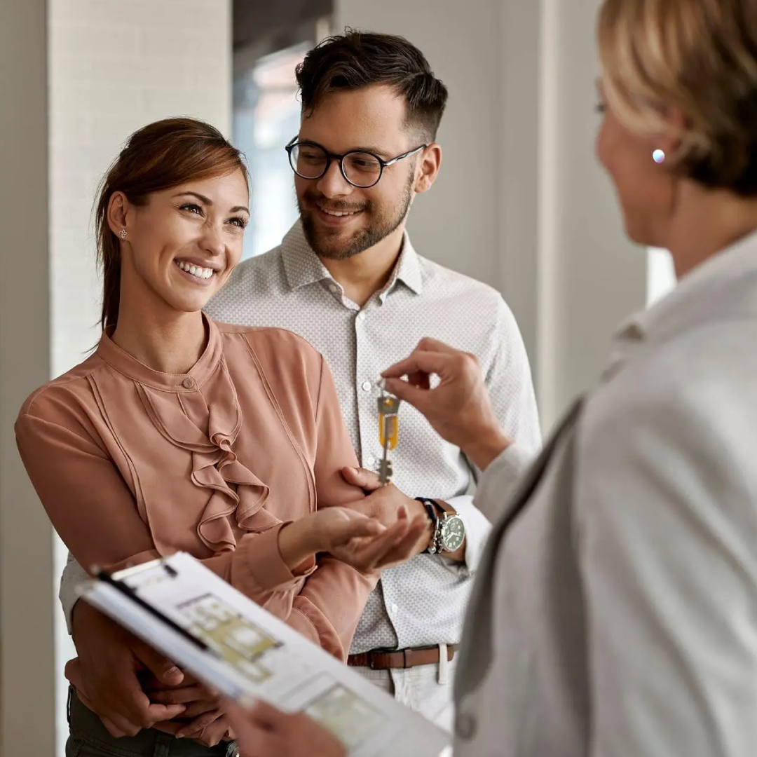 Woman handing keys to married couple